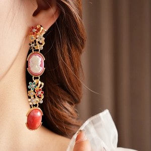 Detail of vintage cameo earrings with floral enamel, rhinestones and red agate drops