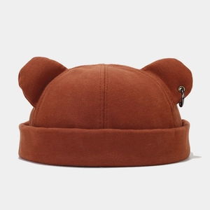 Detailed view of a brown knitted brimless cap with bear ears and a black metal ring