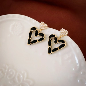 Macro detail of vintage leather woven heart earrings with pearl accents on ceramic