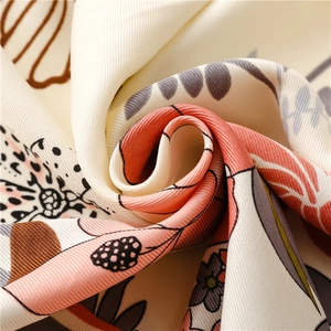 Macro shot of tropical leaf print on beige silk scarf fabric with elegant draped texture