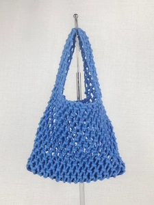 Blue hand-woven mesh beach tote bag with minimalist crochet design on a silver stand