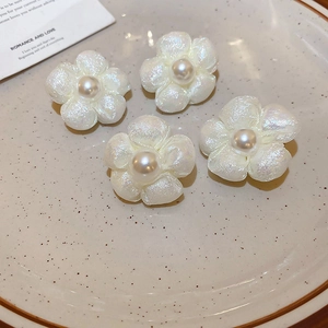 Elegant white fabric flower stud earrings with faux pearls on a ceramic dish