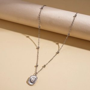 Detail view of a silver cowboy hat pendant with crystal on a delicate beaded chain