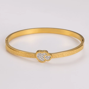 Detailed macro view of gold heart bangle with sparkling sand finish and pave set crystals