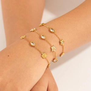 Minimalist gold plated stainless steel bracelet set with floral and star charms on wrist