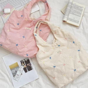 Detail of embroidered colorful bows on checkered canvas shoulder bags with brand tag