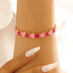 Vista detallada de la pulsera de corazón con dijes de esmalte rojo y rosa en cadena dorada
