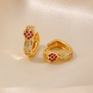 Elegant gold heart earrings with red and white zircons on champagne silk fabric