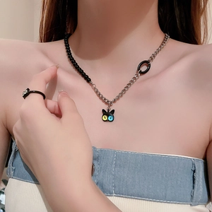 Close-up of a hip-hop style acrylic cat pendant necklace with metallic chain and matching ring