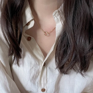 Minimalist gold circle pendant necklace on delicate chain worn with linen shirt