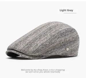 Detail of light gray knit newsboy cap showing thick fabric texture and metal brand tag