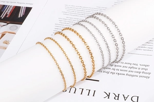 Close-up of sleek gold and silver titanium steel necklaces draped on a white column