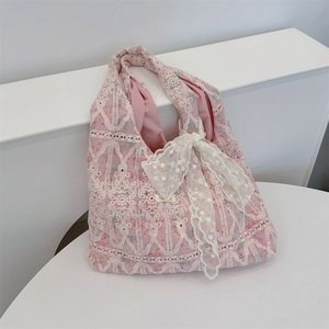 Detail of pink canvas tote featuring intricate white lace embroidery and a large bow