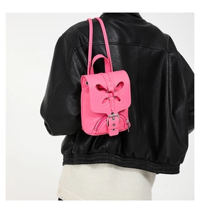 Vue rapprochée détaillée du mini sac à dos en cuir rose avec rabat papillon et boucle.