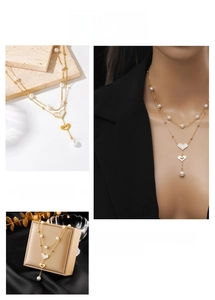Detail of layered gold chain necklace with heart pendant, pearls and gift box