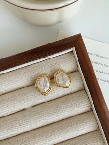 Detailed macro view of French vintage irregular baroque pearl clip earrings in gold