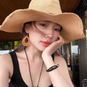 Close-up of raffia drop earrings with straw sun hat for a summer beach vacation style