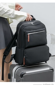 Detail of black nylon backpack with trolley sleeve feature placed on silver luggage