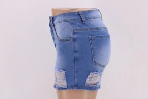 Detail of ripped blue high waist denim shorts with distressed texture and frayed edges
