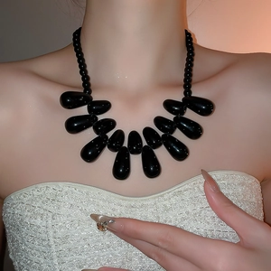 Détail du collier à pendentifs gouttes en acrylique noir porté sur la clavicule