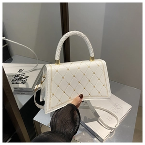 Detail of white quilted handbag with gold hardware, braided handle and star rivet accents