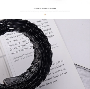 Close-up of black glossy woven belt with a textured interlaced pattern for women