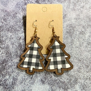 Close-up of buffalo plaid wooden Christmas tree earrings on a brown craft card