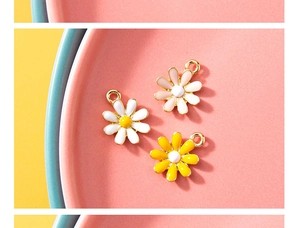 Detailed view of three enamel daisy flower charms with gold edges in various colors