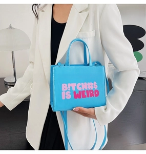 Close-up of sky blue crossbody bag with bold pink text print and adjustable shoulder strap