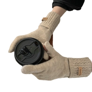 Gants tricotés en cachemire beige pour femmes tenant une tasse de café chaud
