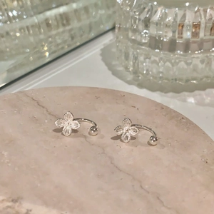 Close-up of silver hollow flower ear clips with delicate U-shape design