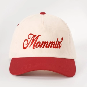 Close-up of Mommin' embroidery on a two-tone beige and red cotton baseball cap