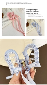 Dettaglio della molletta per capelli in raso con lunghi nastri rosa e azzurro