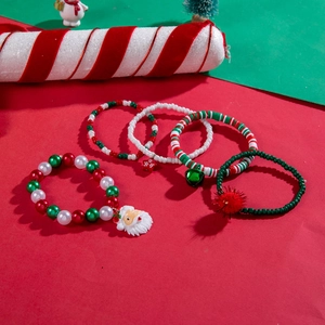 Detailed view of five Christmas beaded bracelets with Santa, bell, and star charms