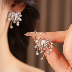 Macro shot of silver earring with sparkling zircon firework design and pearl detail