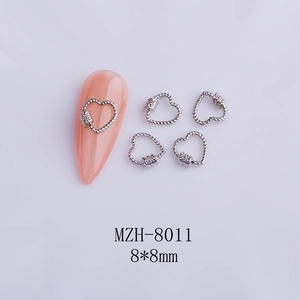 Macro shot of silver metal heart nail charms with textured braided pattern details