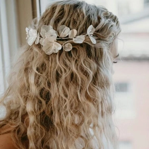 Detail of white fabric floral bridal headband with bead accents on wavy hair