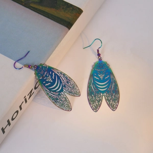 Macro shot of iridescent laser-cut cicada earrings with intricate hollow wing textures