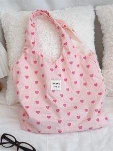 Pink heart print canvas tote bag with brand label on a soft home lifestyle background