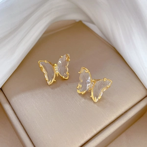 Detail shot of crystal butterfly earrings with gold plating on premium silk background