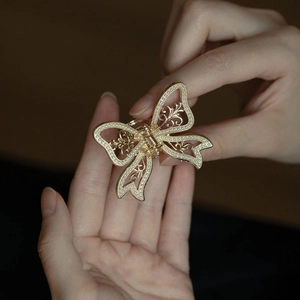 Elegant gold metal bow hair claw clip with pearl embellishments and hollowed design