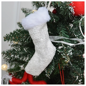 Close-up of white and silver tweed Christmas stocking ornament on a festive tree branch