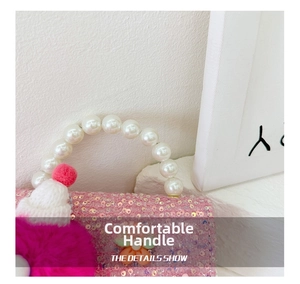Detail of pink sequin girl's handbag featuring pearl bead handle and fuzzy pompom decor
