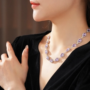 Macro shot of a vintage teardrop necklace with purple crystal and diamonds on model