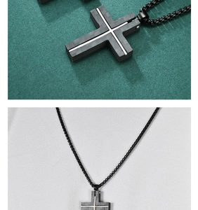 Close-up of black carbon fiber titanium cross pendant with silver stripes on green paper