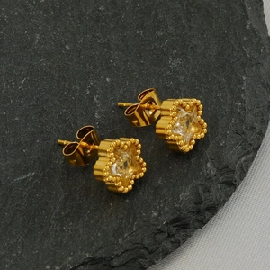 Detailaufnahme goldener Stern-Ohrstecker mit Zirkonia auf grauem strukturiertem Stein