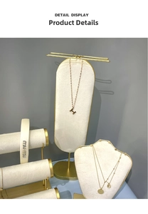 Detail view of gold letter necklaces and a white satin headband on a velvet display stand