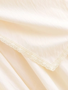 Detailed macro view of the cream fabric texture and delicate lace edge on the skirt