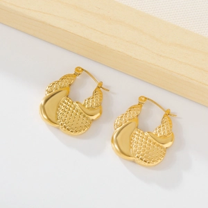 Macro detail showing woven mesh texture and polished gold finish on steel earrings