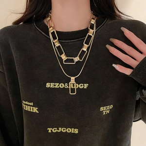 Detail showing a layered gold chain necklace featuring a chunky link and a snake chain